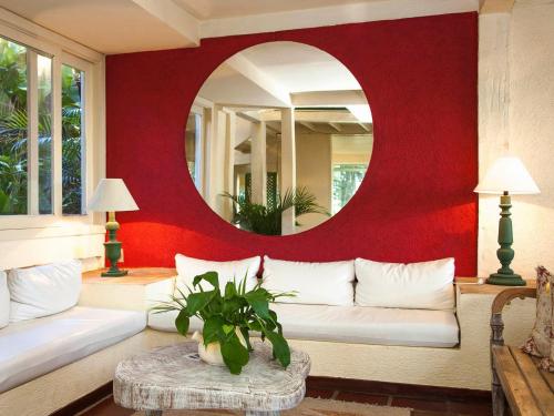 a living room with a white couch and a mirror at Hotel Pousada Casacolina in Búzios