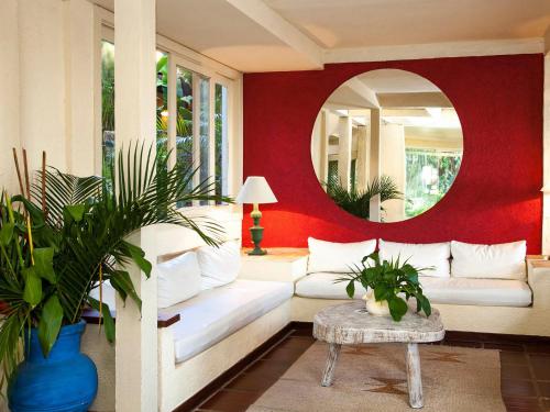 a living room with a white couch and a mirror at Hotel Pousada Casacolina in Búzios