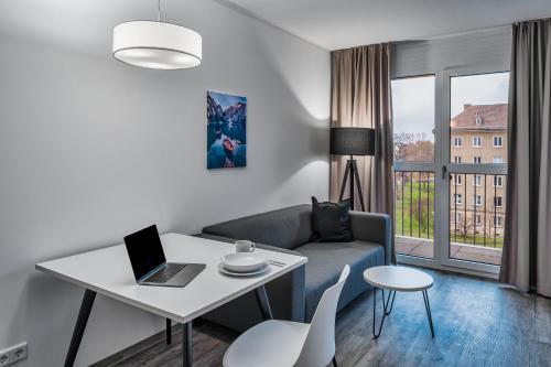 a living room with a couch and a table with a laptop at NorthApartments Dresden am Park in Dresden