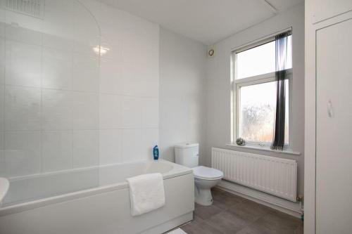 a white bathroom with a tub and a toilet at Cozy 3 bedroom house @ Hömli in Loughborough