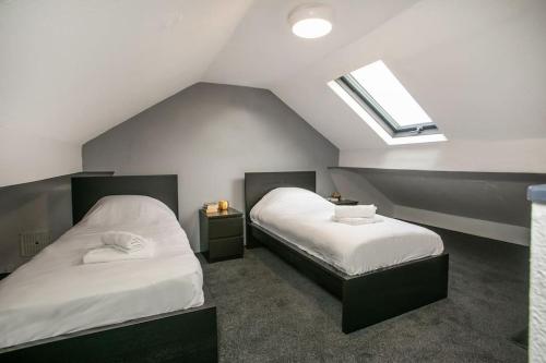 two beds in a room with a slanted ceiling at Cozy 3 bedroom house @ Hömli in Loughborough