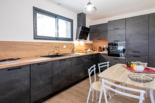 une cuisine avec des armoires noires et une table en bois dans l'établissement Villa Renajolo 6 pers 3 min plage en voiture, à Sainte-Lucie de Porto-Vecchio