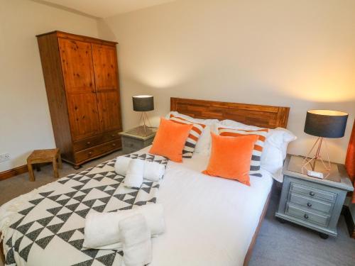 カークビー・ロンズデールにあるOld Farm Cottageのベッドルーム1室(大型ベッド1台、オレンジと黒の枕付)