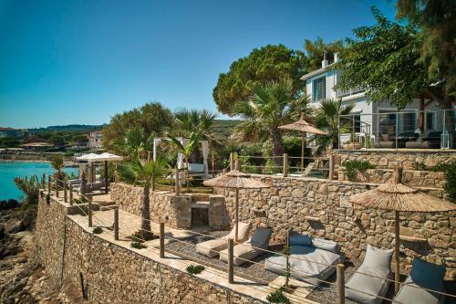 a stone wall with chairs and umbrellas at Paradisso Beach Villas in Zakynthos Town