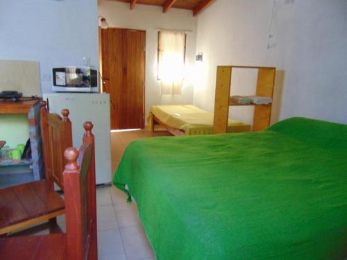 Habitación pequeña con cama verde y cocina en Aldea Serrana en Tandil