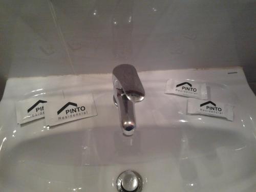 a bathroom sink with a faucet and two stickers on it at Residencial Pinto in Guarda