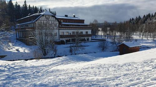 a large building in the snow with snow covered ground at Wellness apartmán Pila na Kvildě in Kvilda