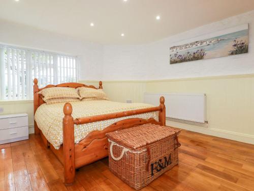 a bedroom with a wooden bed with a wicker basket at Carew Lodge & Loft in Torpoint
