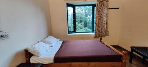 um pequeno quarto com uma cama e uma janela em Green House Rock Home Stay em Chinnakanal