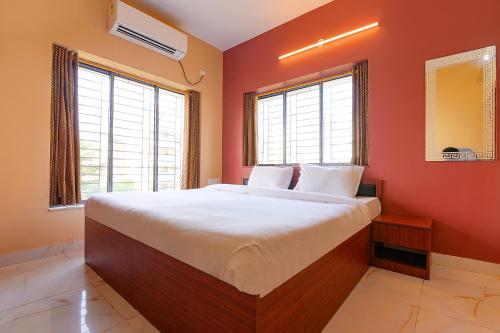 a bedroom with a large bed with red walls and windows at FabHotel Amar Raj Inn in Kolkata