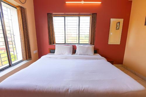 a large bed in a red room with two windows at FabHotel Amar Raj Inn in Kolkata