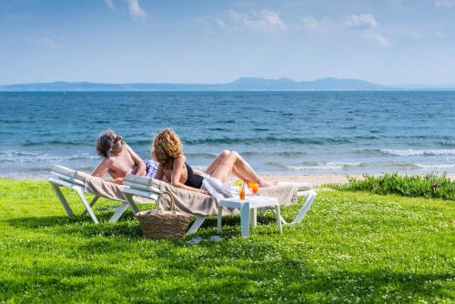 two people sitting on lawn chairs on the beach at Hotel & Spa Terraza 4 Sup in Roses