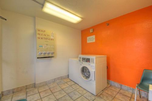 a washing machine in a laundry room with an orange wall at Motel 6 San Antonio, Tx Six Flags Fiesta TX - La Cantera Area in San Antonio
