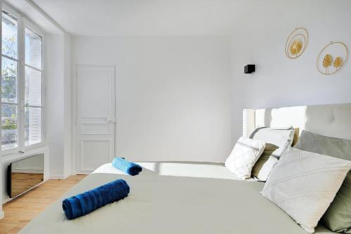 - une chambre blanche avec un lit et des oreillers bleus dans l'établissement Appartement - Stade de France, à Saint-Denis