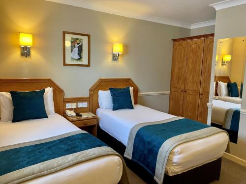 a hotel room with two beds with blue pillows at Harcourt Hotel in Dublin
