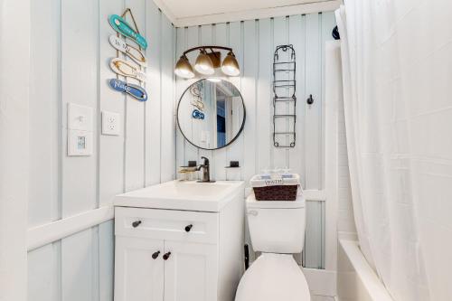 uma casa de banho com um WC branco e um espelho. em Beach House em Kill Devil Hills