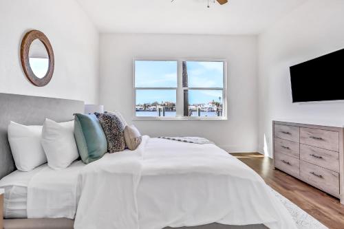 a white bedroom with a bed and a television at Indian Rocks Beach Hideaway in Clearwater Beach