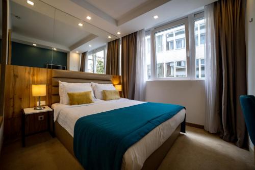 ein Schlafzimmer mit einem großen Bett mit einer blauen Decke in der Unterkunft MARK Hotel in Belgrad