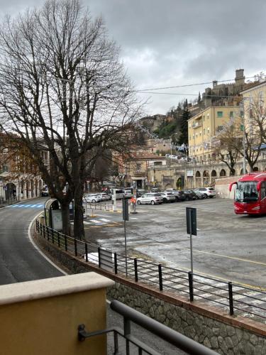 a street with a parking lot with a red bus at Rainbow Hotel Depandance Joli in San Marino
