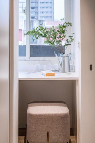a stool in front of a window with a plant at Lin Suites by Olala Homes in Taipei