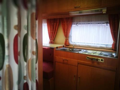 una pequeña cocina con fregadero y ventana en Wellnester Tiny Houses and Retro-Caravan by the lake in Losheim am See en Losheim
