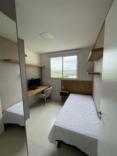 a bedroom with a bed and a desk and a window at Apartamento 2 quartos c/ Piscina 3 Ar-condicionado in Torres