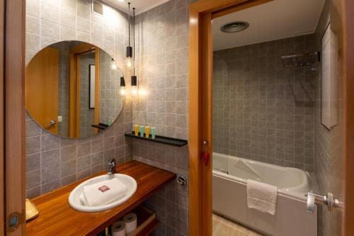 a bathroom with a sink and a tub and a mirror at Apartament l'Osset in La Molina