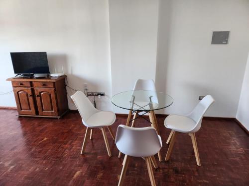 a dining room with a glass table and white chairs at Departamento Centro in San Fernando del Valle de Catamarca