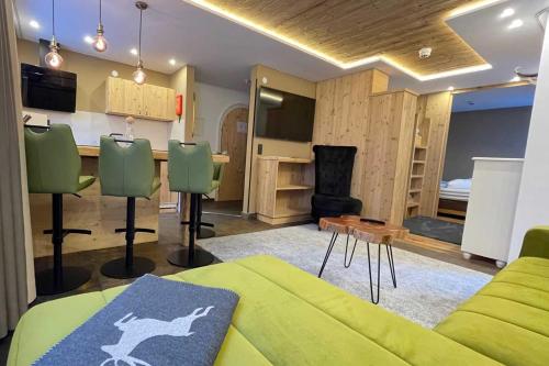 a living room with a green couch and a kitchen at Quality Hosts Arlberg - ALPtyrol Appartements in Sankt Anton am Arlberg