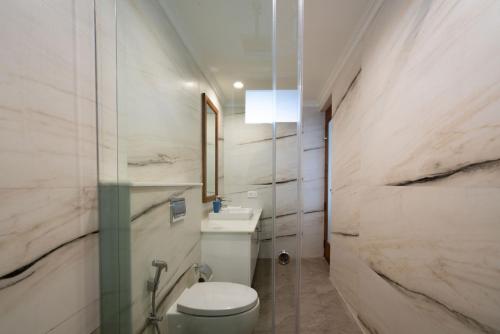 y baño con aseo blanco y lavamanos. en StayVista at Paradise Valley View with Terrace Access, en Munnar