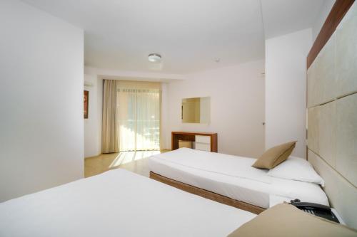 two beds in a room with white walls at Delfino Apart Hotel in Alanya