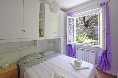 1 dormitorio con 1 cama con cortinas moradas y ventana en VILLA BARBARA, en Zoagli