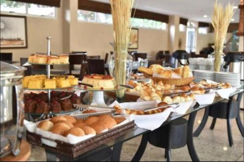 a table filled with different types of bread and pastries at Gran Lençóis Flat Barreirinhas Apt 509 in Barreirinhas