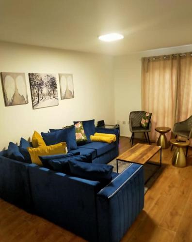 a living room with a blue couch and yellow pillows at Impeccable 2-Bed House in London