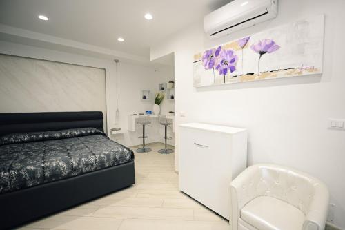 1 dormitorio blanco con 1 cama y 1 silla en Gandrè Room, en Mesagne