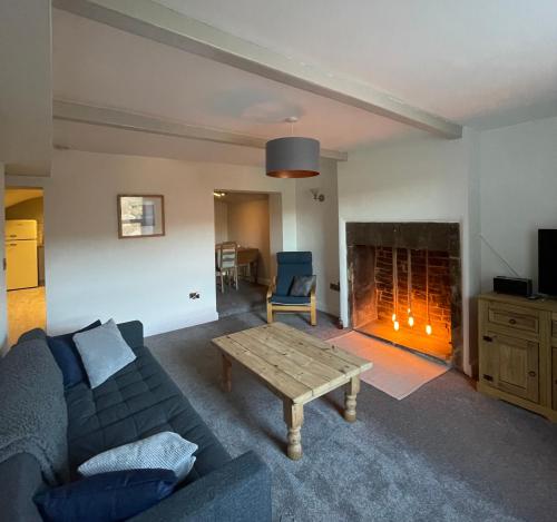 a living room with a couch and a fireplace at Brook Cottage in Holmfirth