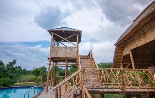ein Baumhaus mit einer Terrasse neben einem Pool in der Unterkunft NKUNDWA NILE VIEW LODGE in Wanseko