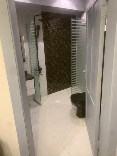 a bathroom with a black toilet and a glass door at Orchid Tarif Serviced Apartments 1 شقق أوركيد طريف للشقق المخدومة 1 in Ţurayf
