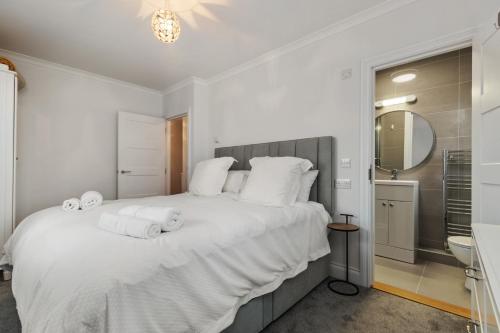 sypialnia z dużym białym łóżkiem z ręcznikami w obiekcie Cottage Mews - Seaside Cottage Parking Terrace w mieście Tenby