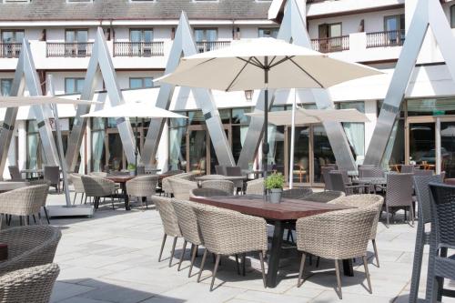 un patio al aire libre con mesas, sillas y sombrillas en Coppid Beech en Bracknell