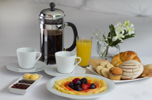 a table with plates of breakfast foods and a coffee maker at Hotel Rio 1300 in Cuernavaca