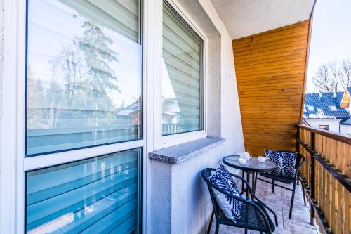 a balcony with a table and chairs and a window at Apartament Bystry Potok in Zakopane