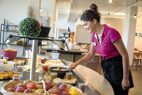 une femme prépare sa nourriture sous forme de buffet dans l'établissement Belambra Clubs Trégastel - Le Castel Sainte Anne, à Trégastel