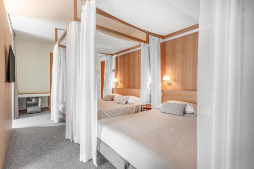 a bedroom with two beds with white curtains at Albergo Sorriso in Boario Terme