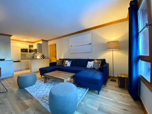 ein Wohnzimmer mit einem blauen Sofa und einem Tisch in der Unterkunft Big Tartiflat, Arc 1950, 2 bed ski-in ski-out in Bourg-Saint-Maurice