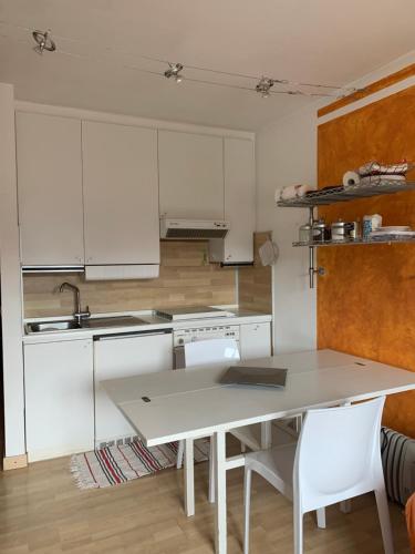 - une cuisine avec des placards blancs, une table et des chaises dans l'établissement Chez Nous, à Foppolo