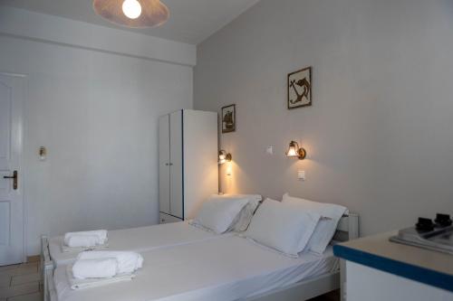 a white bedroom with a bed with white sheets and pillows at Studios Alsos in Naxos Chora