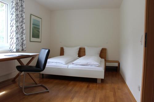 een bed in een kamer met een bureau en een stoel bij Boardinghouse My Maison in Morschen