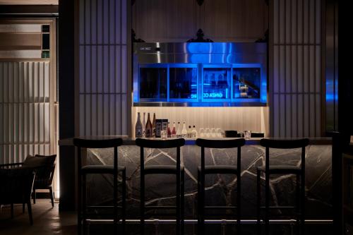 a bar with four bar stools in a room at The Royal Park Canvas Ginza Corridor in Tokyo
