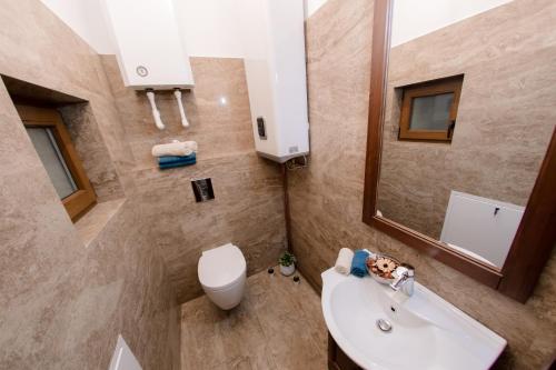 Un baño con lavabo, inodoro y espejo. en Luxury Down Town, en Bucarest